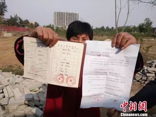 村民手中的土地使用证以及和村委会签订的征地协议。　王天译 摄